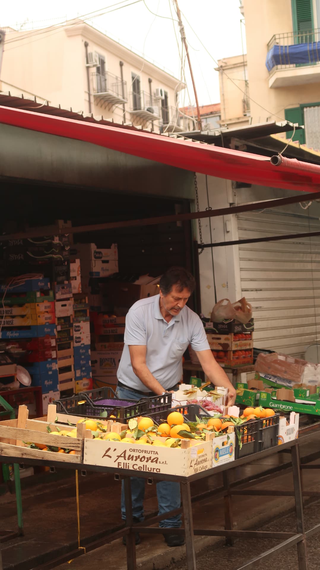 Market vendor behind crates of oranges on a Palermo stall