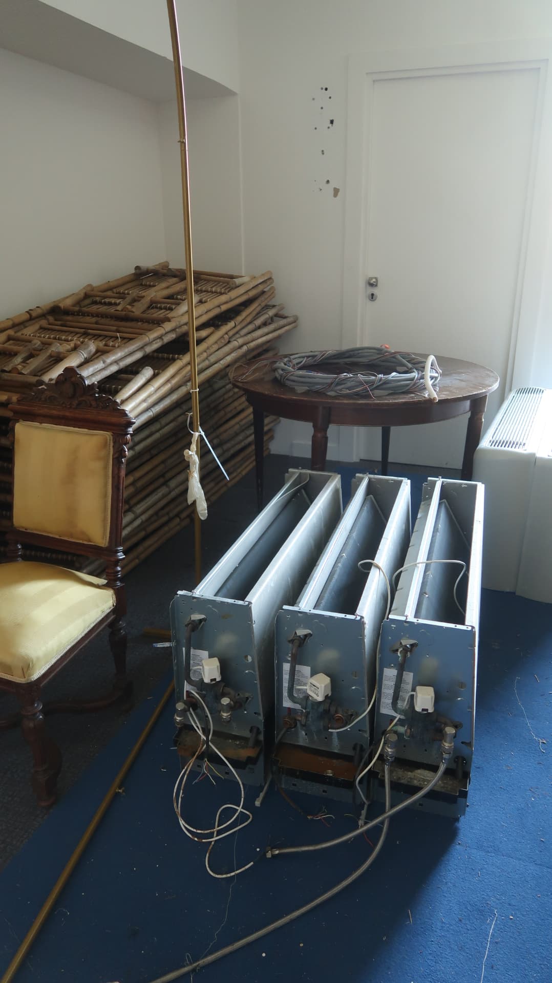 Stacked bamboo, a gilt chair and dismantled radiators