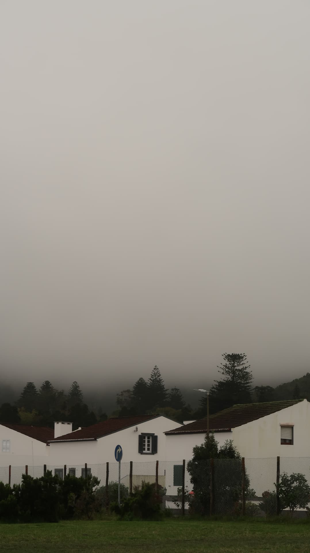 White houses with tiled roofs below a hillside swallowed by fog
