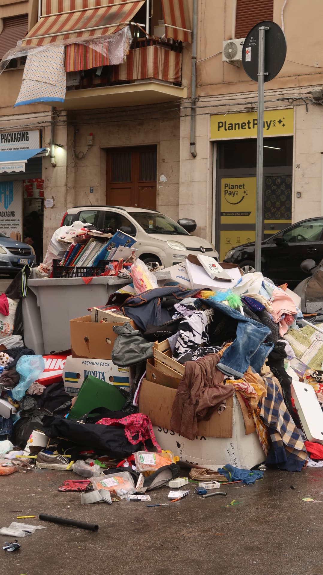 Street corner with a large pile of discarded clothing and objects before old shopfronts