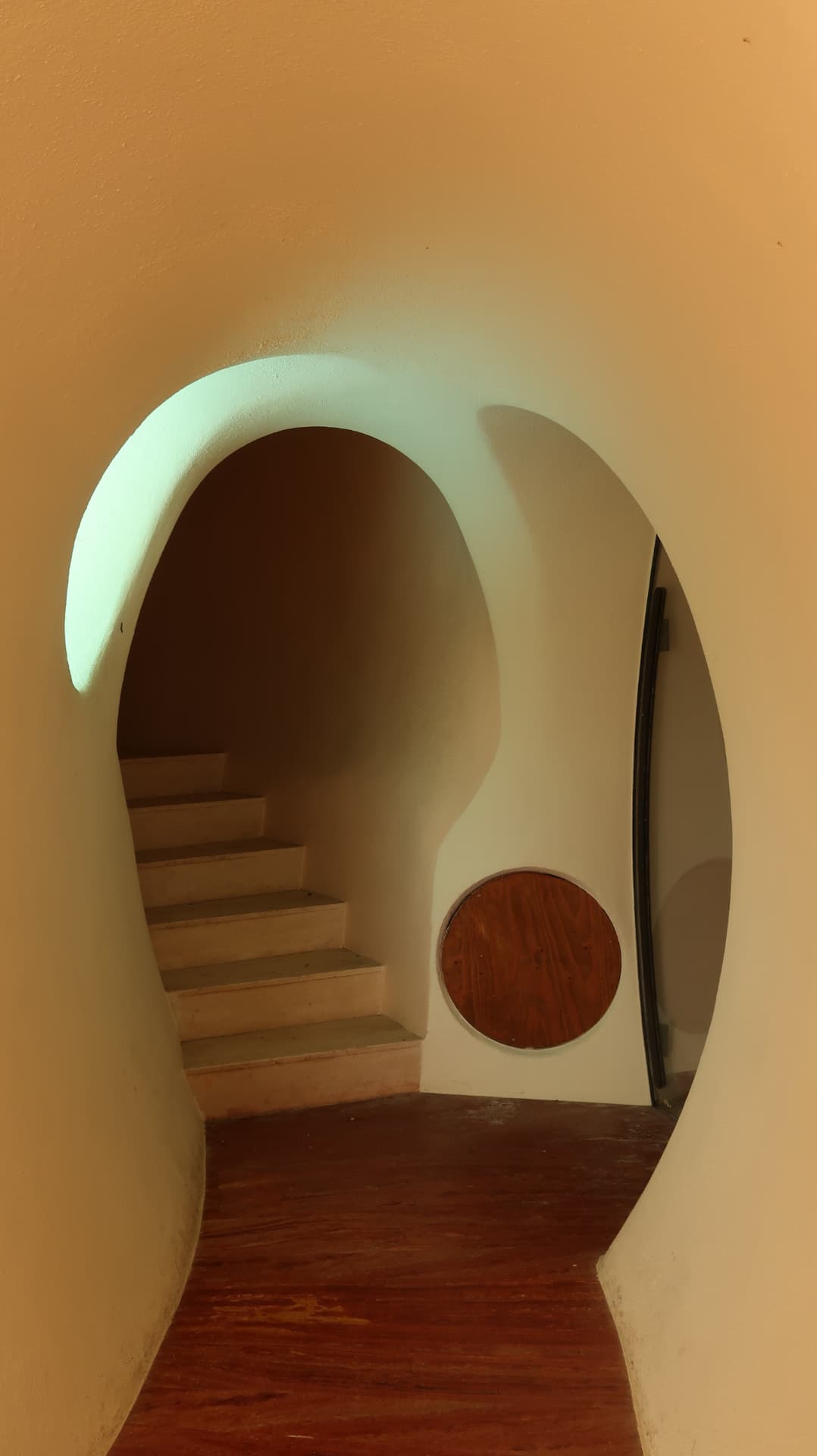 Rounded stairwell opening with a circular timber hatch and red floor