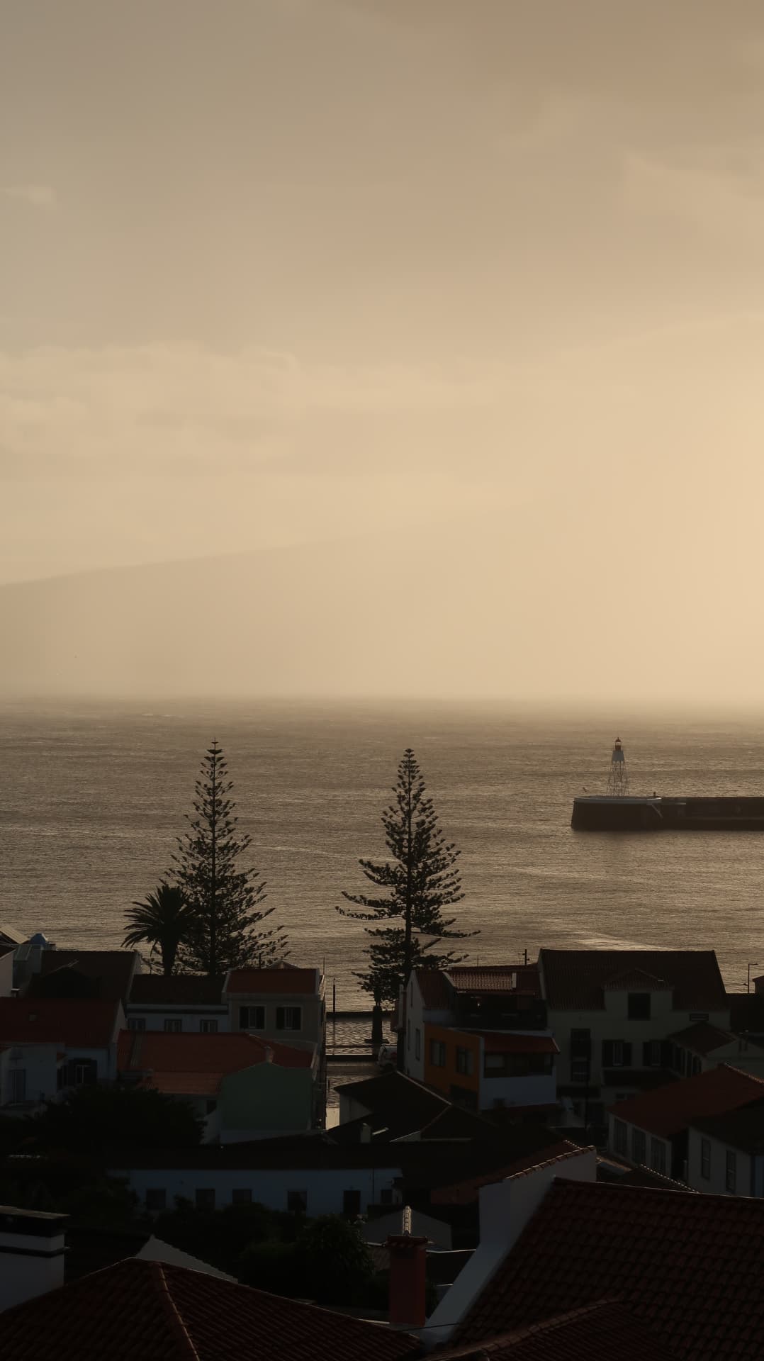 Harbour town at dusk with sea mist and a lighthouse pier
