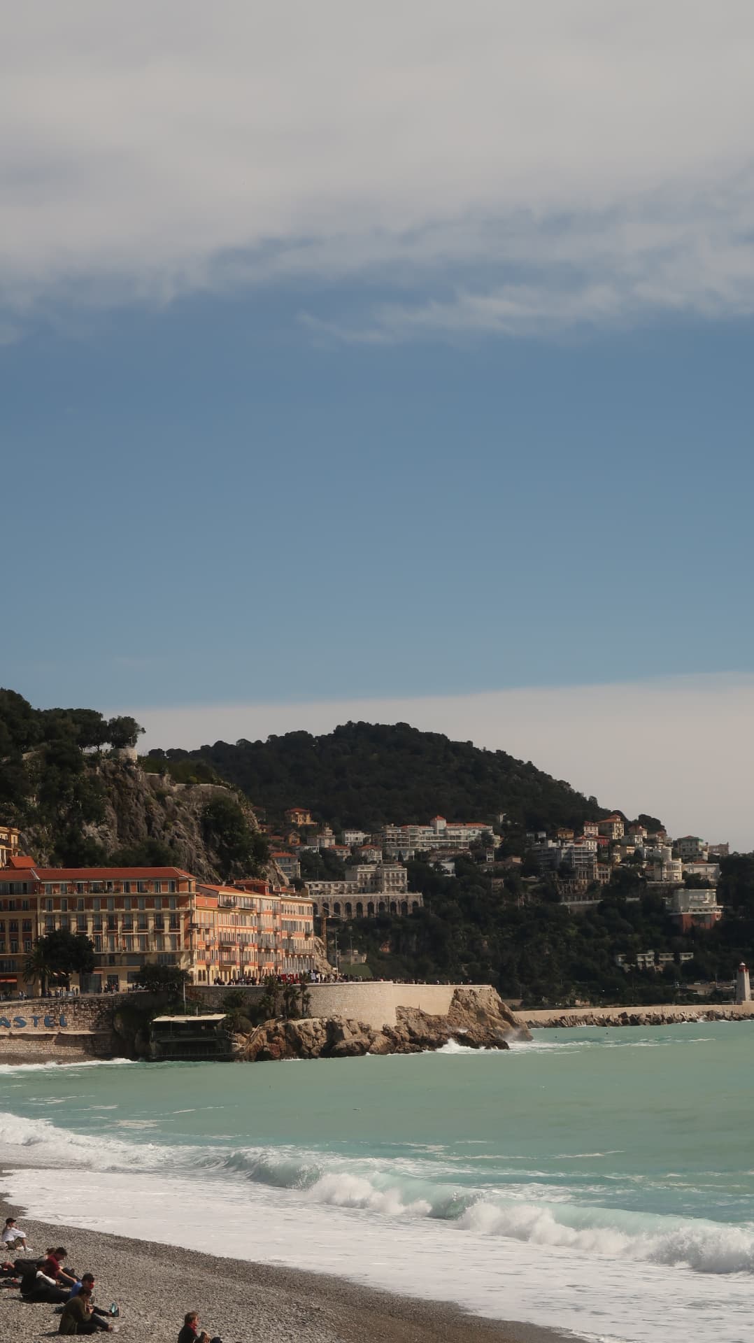 Castel beach with turquoise surf and the hill of Nice beyond