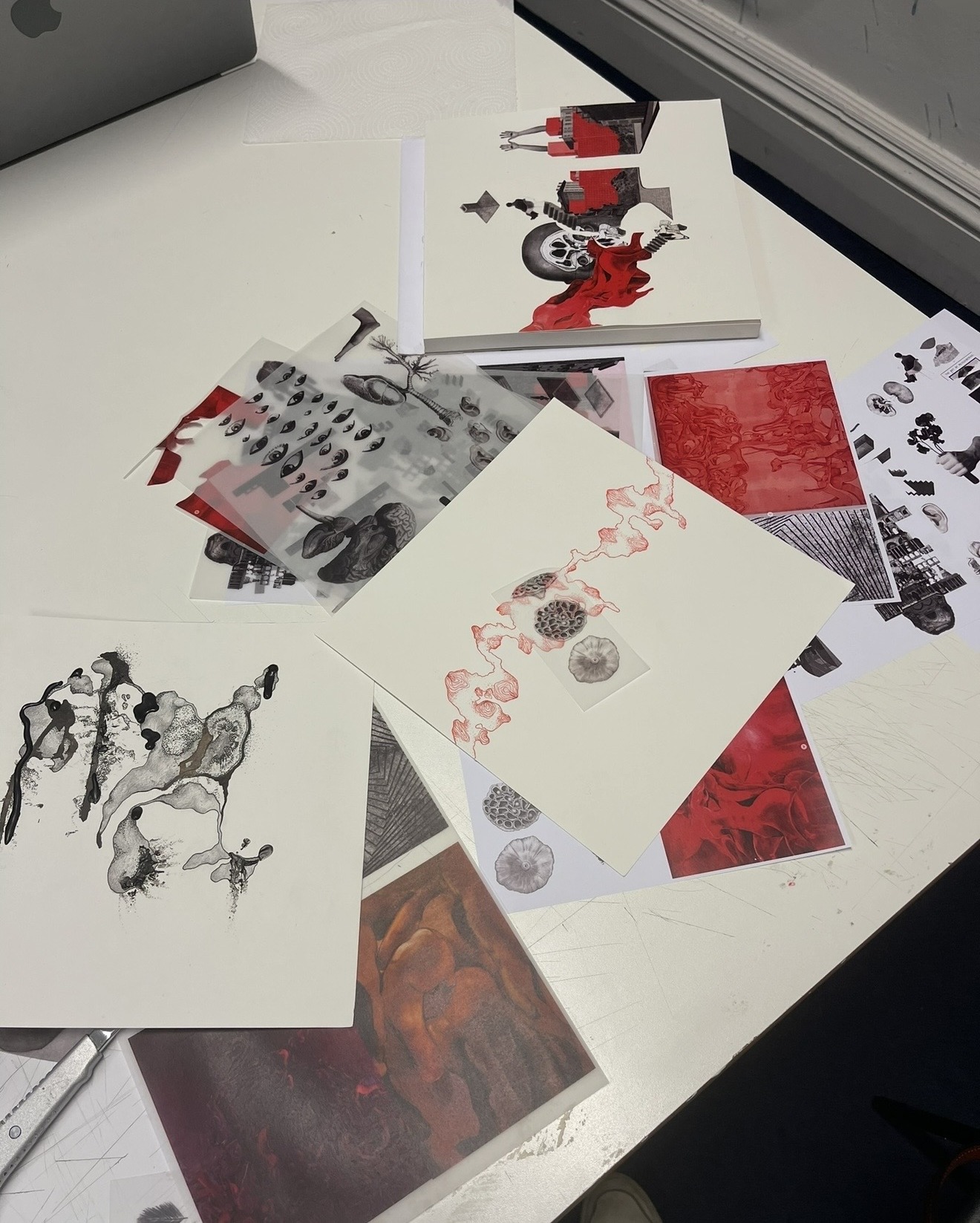 Prints, collages and ink studies laid out across the desk