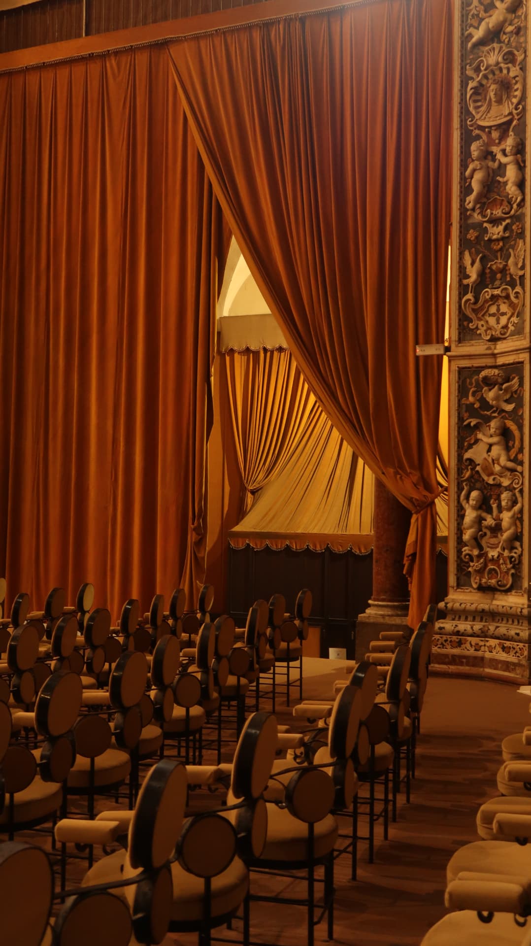 Terracotta stage curtains and rows of round-backed chairs