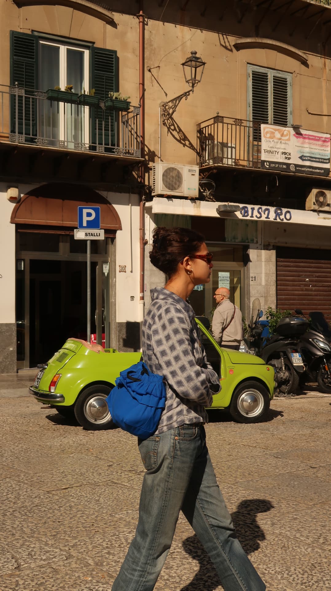 Woman walking past a lime green Fiat 500 in a Palermo street