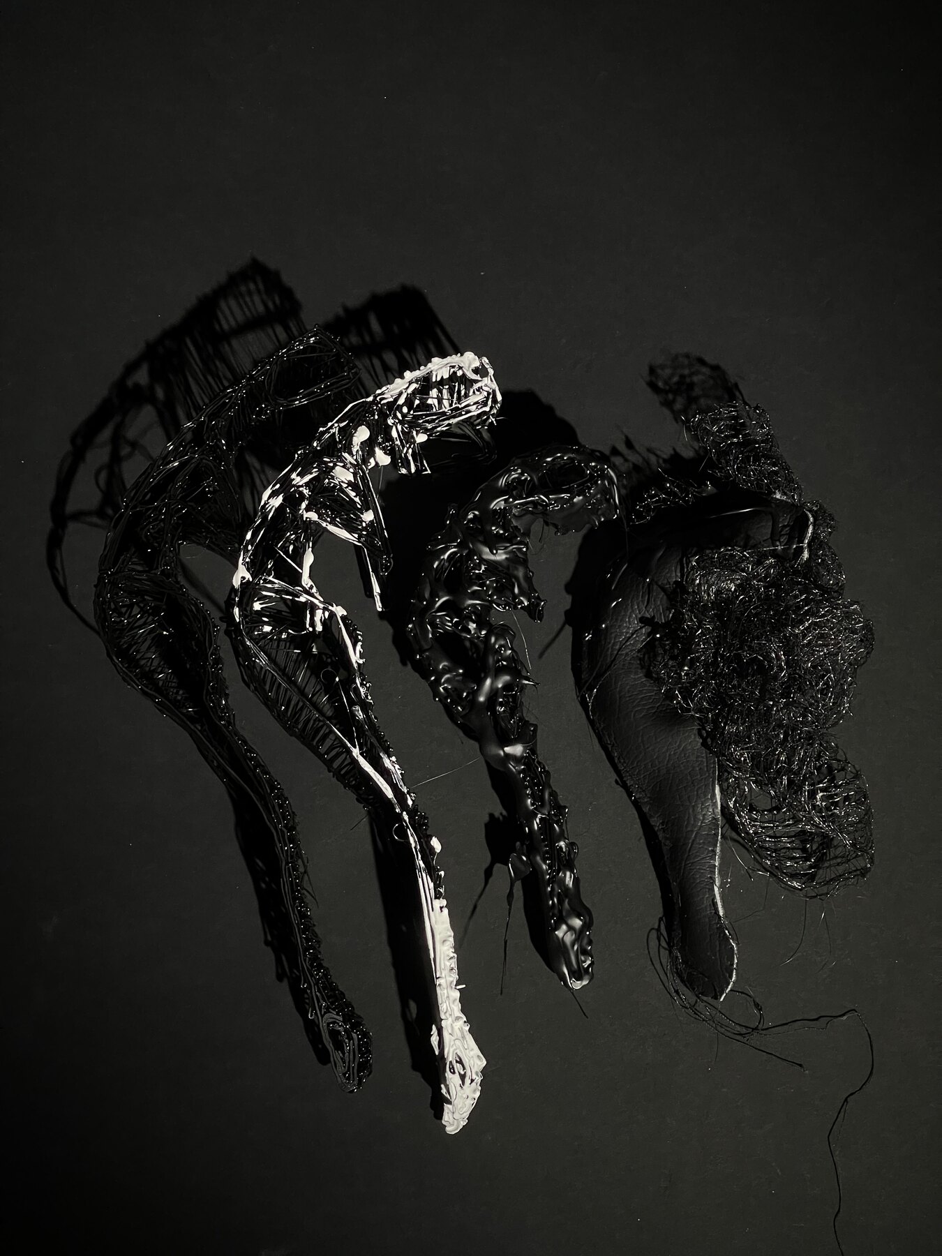 Black wire and resin limbs assembled against a dark ground