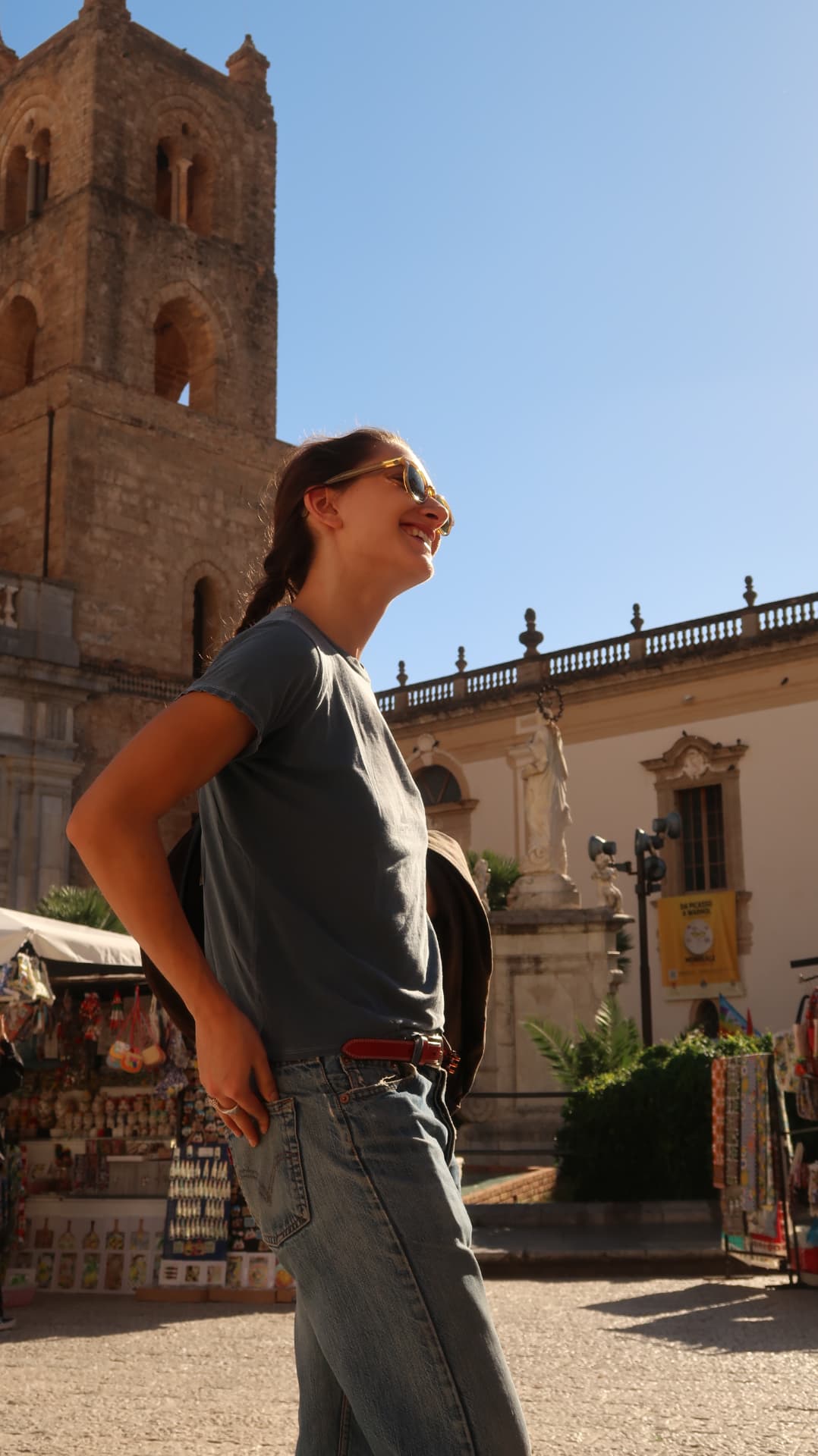 Woman laughing in the sun before the bell tower of Monreale cathedral