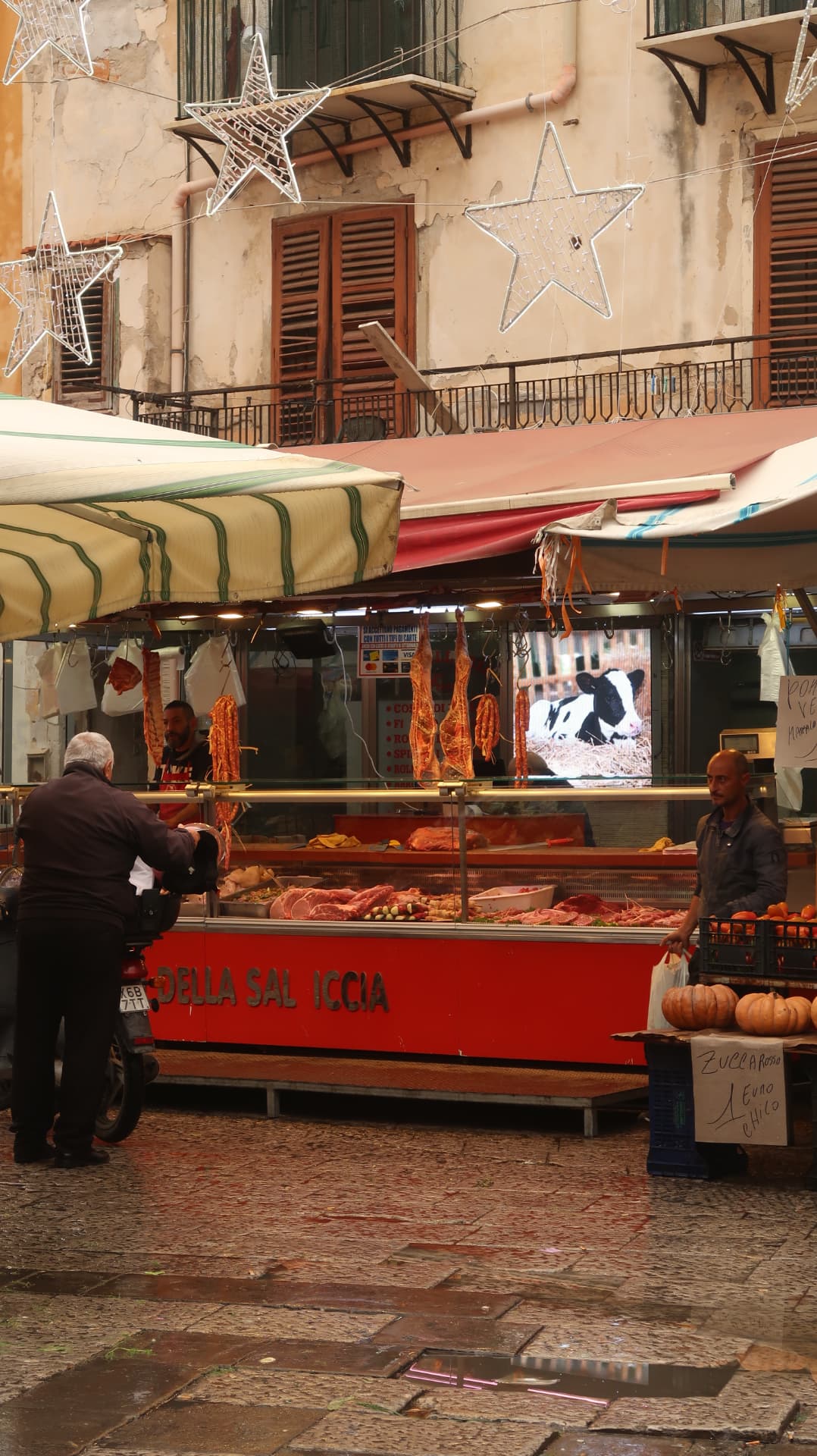 Butcher stall in a market with hanging sausage and Christmas star lights