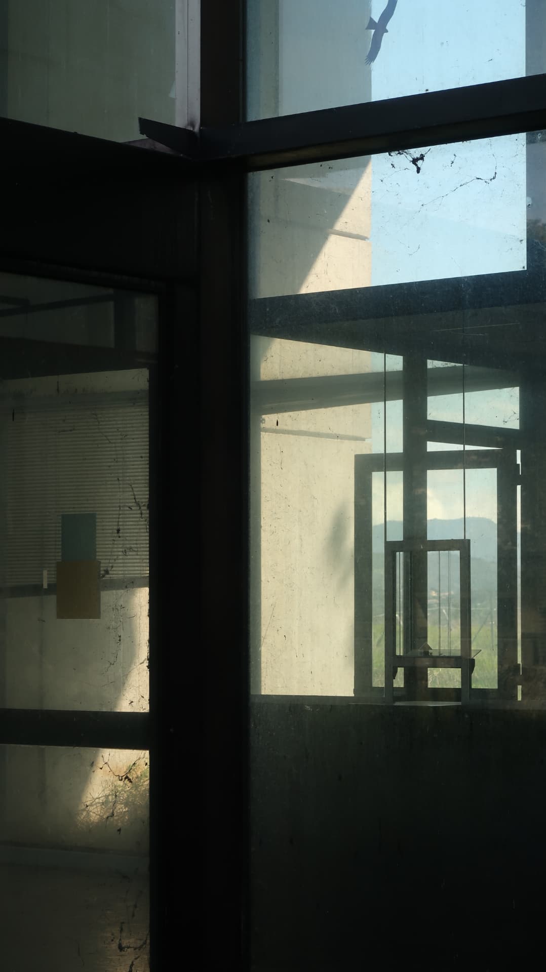 Mullions and reflections layered through dusty glazing