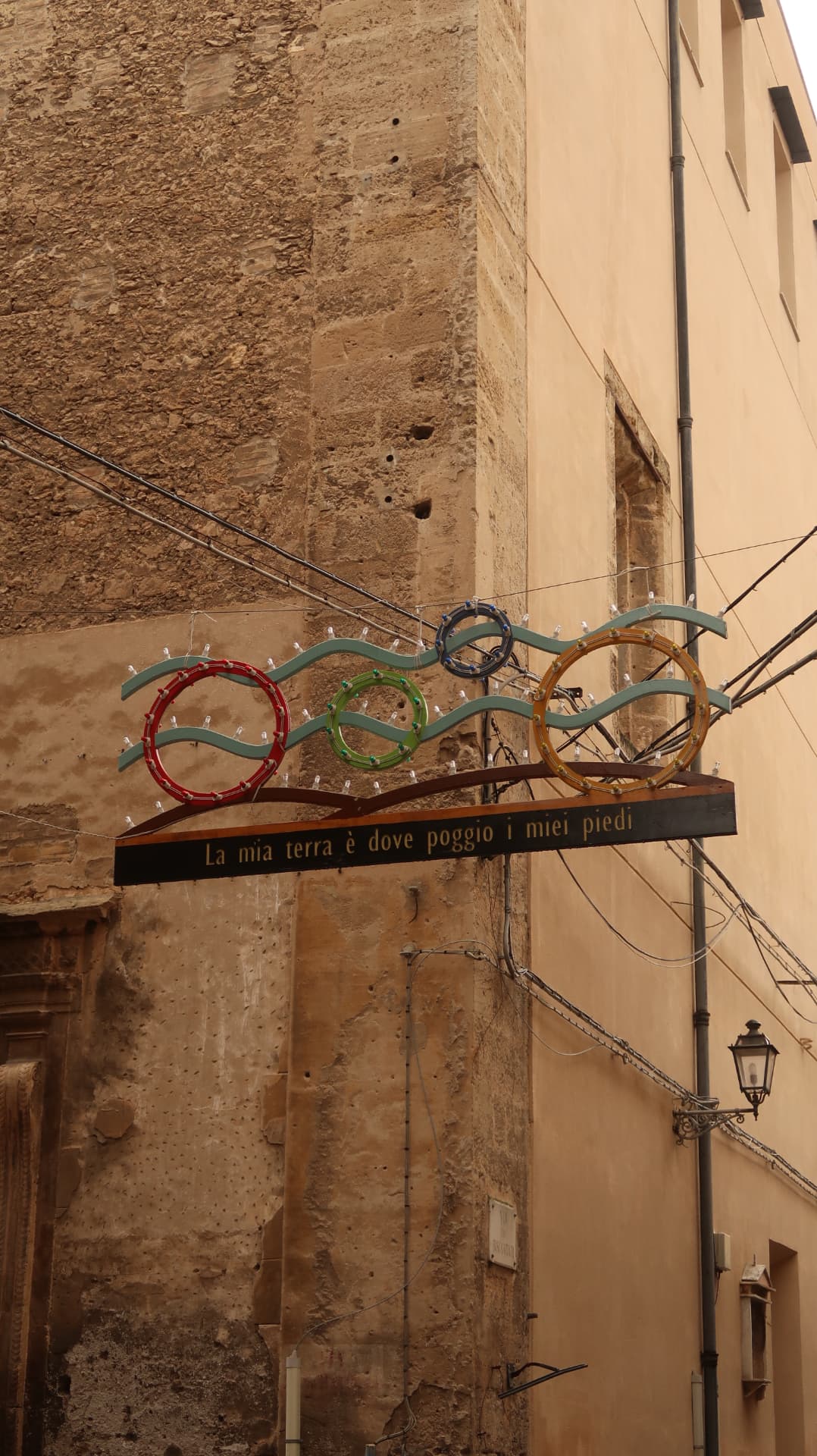 Stone alley facade with a sign reading La mia terra è dove poggio i miei piedi