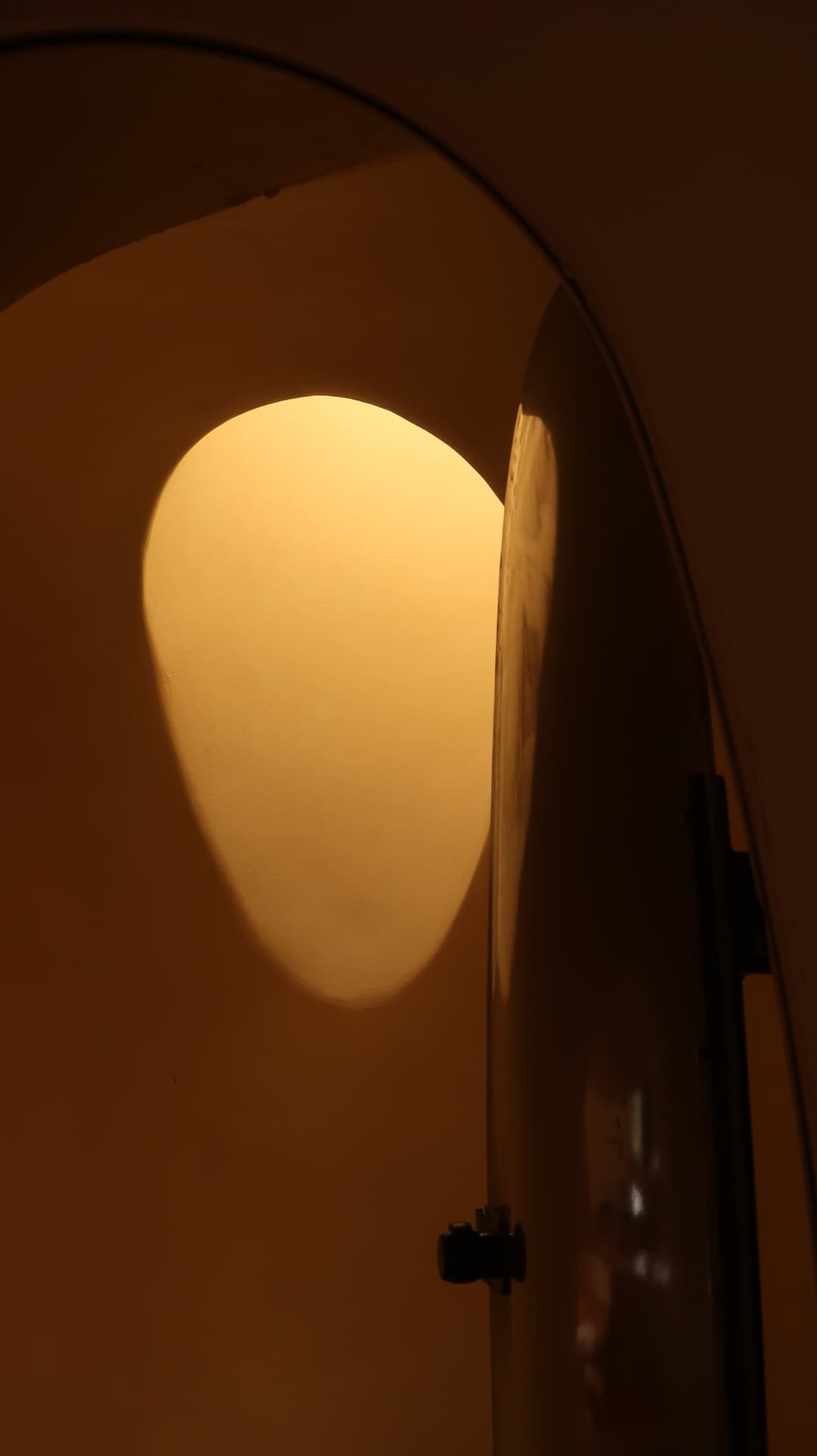 Warm light falling in an egg shaped patch beside a steel door