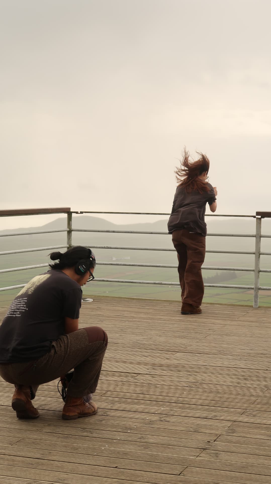 Two people photographing from a viewing deck in wind