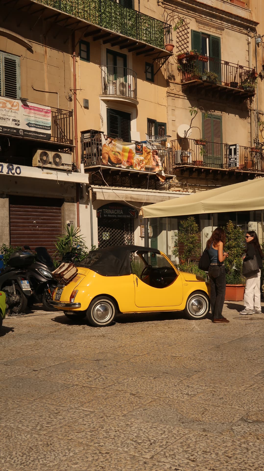 Yellow vintage Fiat 500 convertible parked in a Palermo square