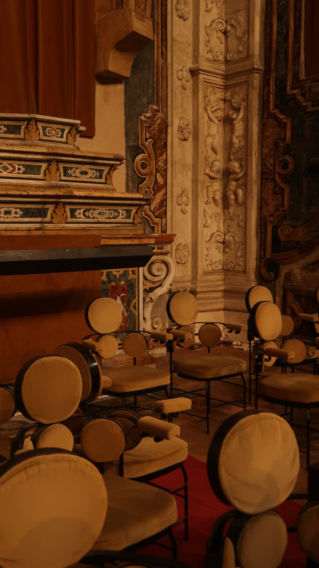 Ornate church interior with carved stone columns and velvet chairs