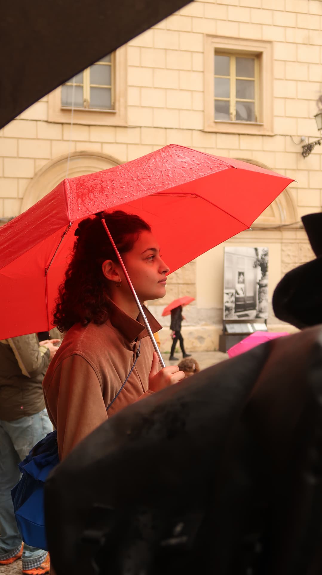 Woman under a red umbrella in a rainy courtyard
