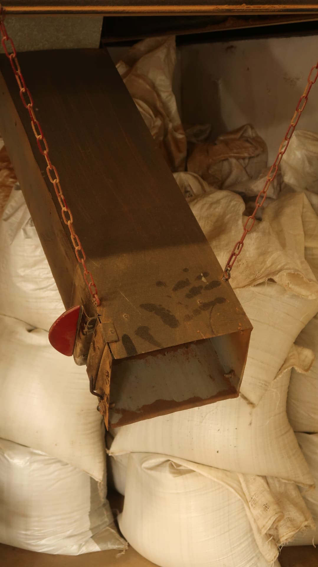 Hanging metal chute above stacked white sacks