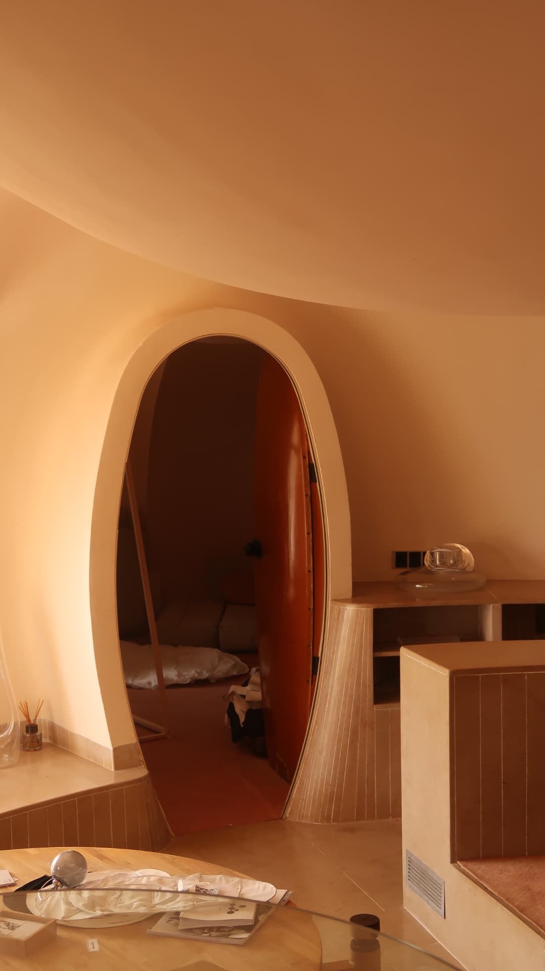 Oval doorway onto a bedroom with a red lacquer door and curved ceiling