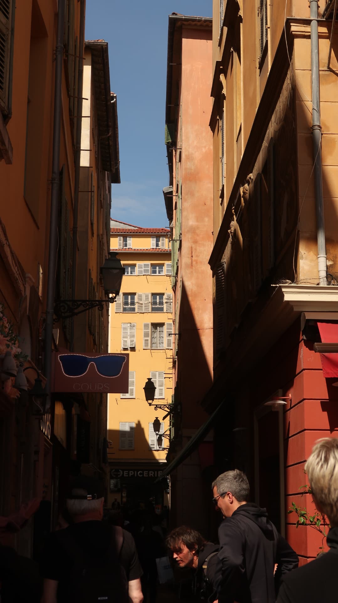 Narrow old town alley in raking light with hanging shop signs