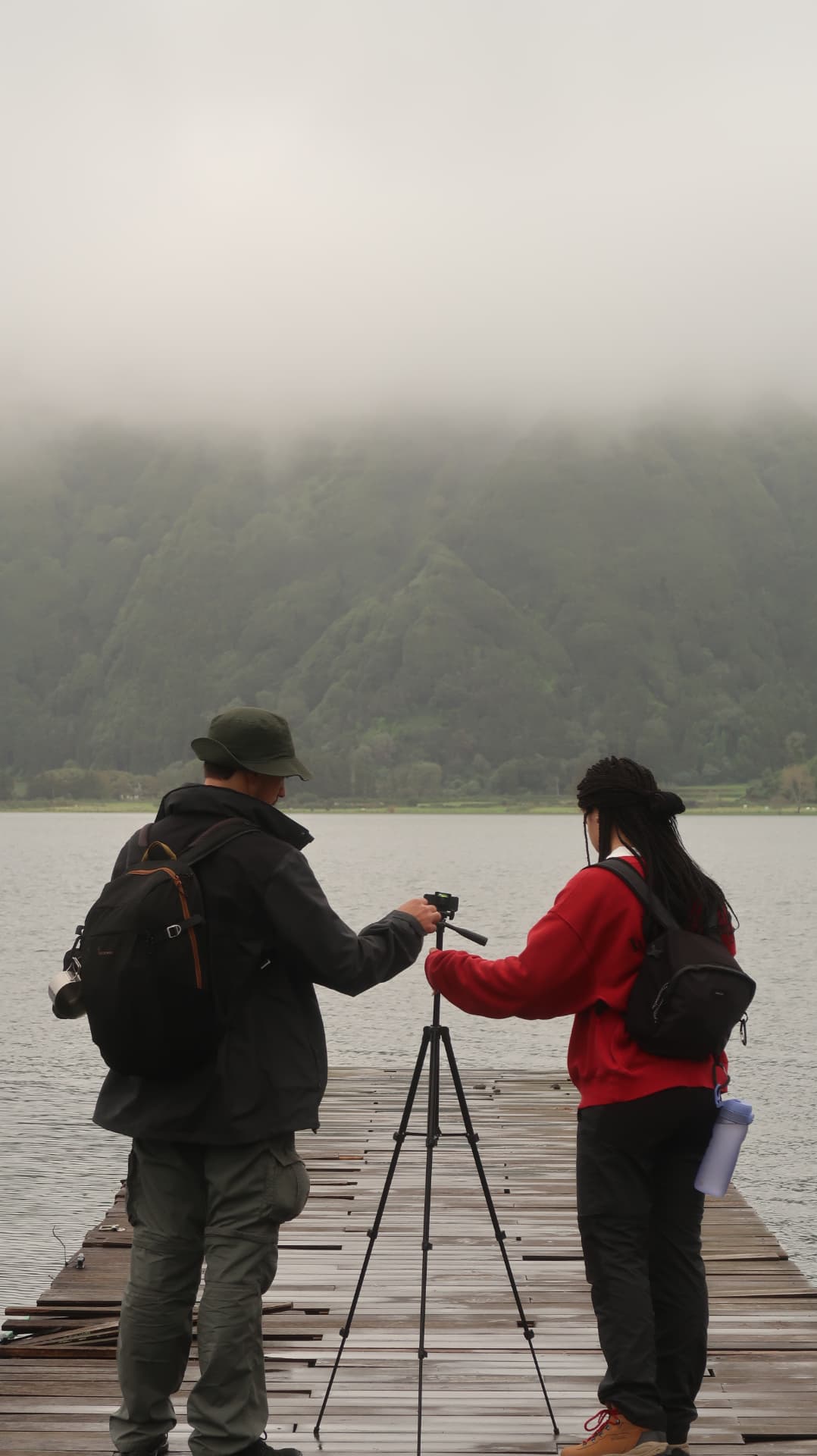 Two photographers with a tripod on a lake jetty