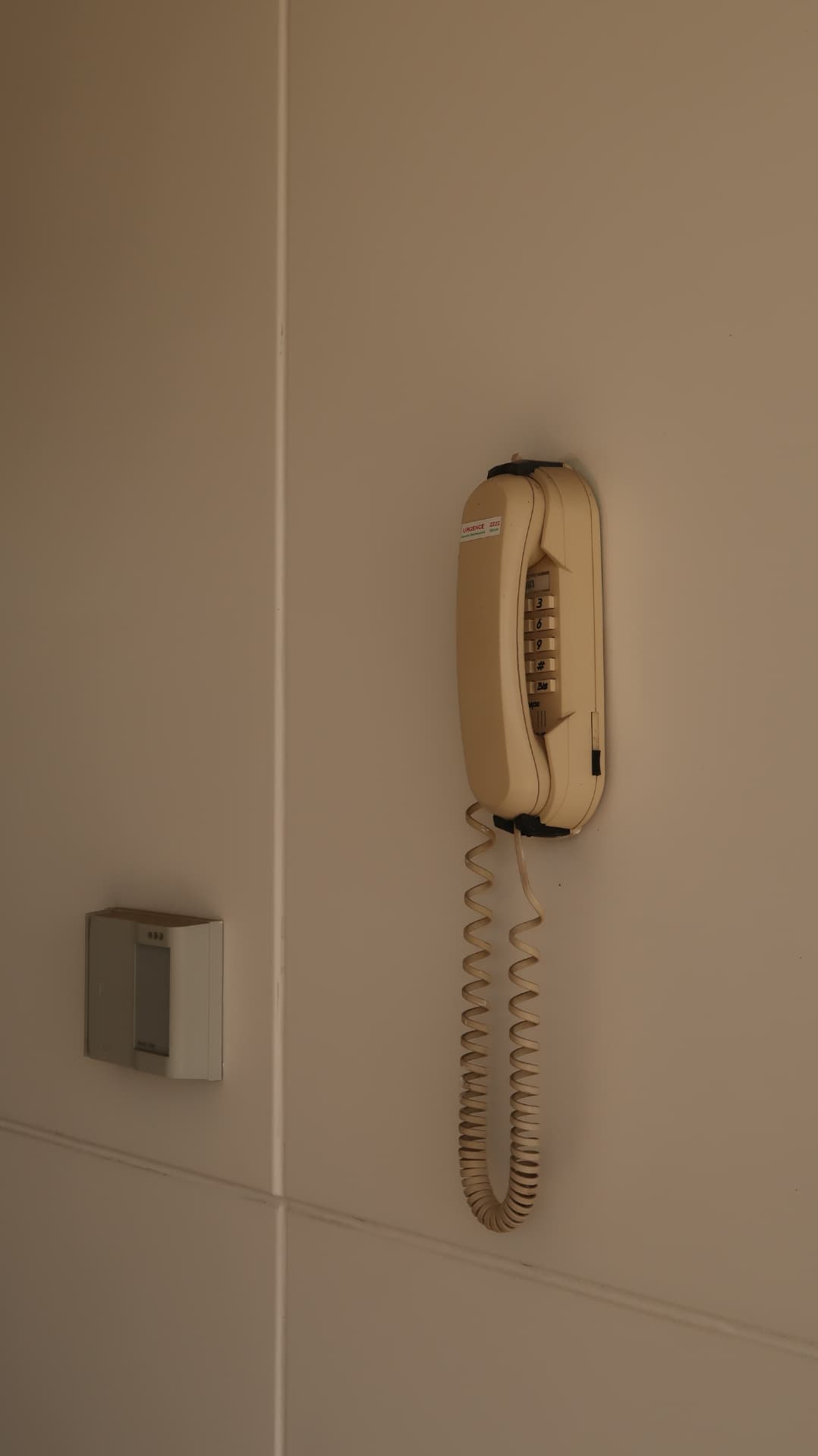 Cream wall telephone with a coiled cord