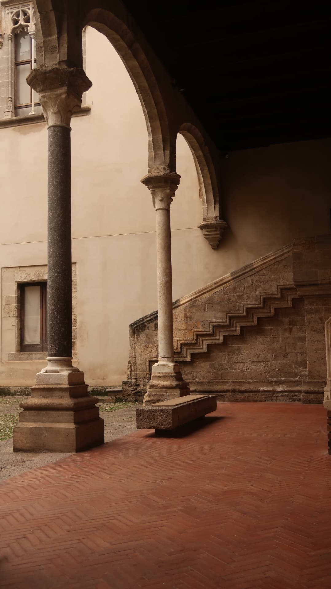 Gothic cloister arches over a herringbone brick courtyard