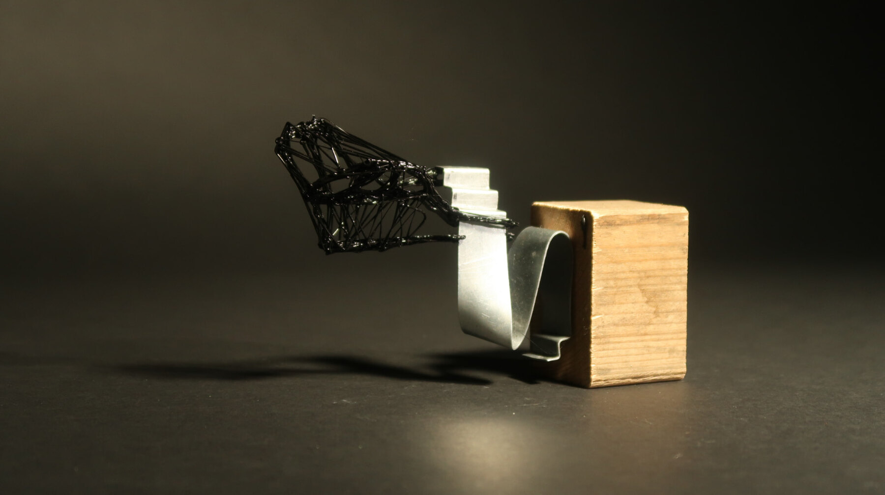 Model of a black wire canopy cantilevered from a folded metal sheet
