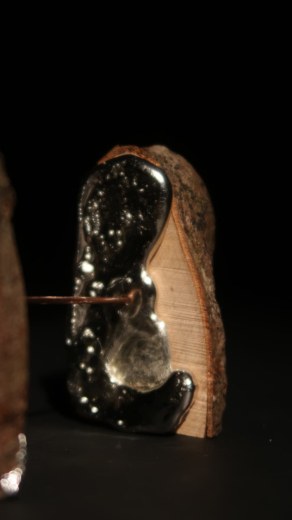 Close detail of dark glassy resin poured against a sawn face