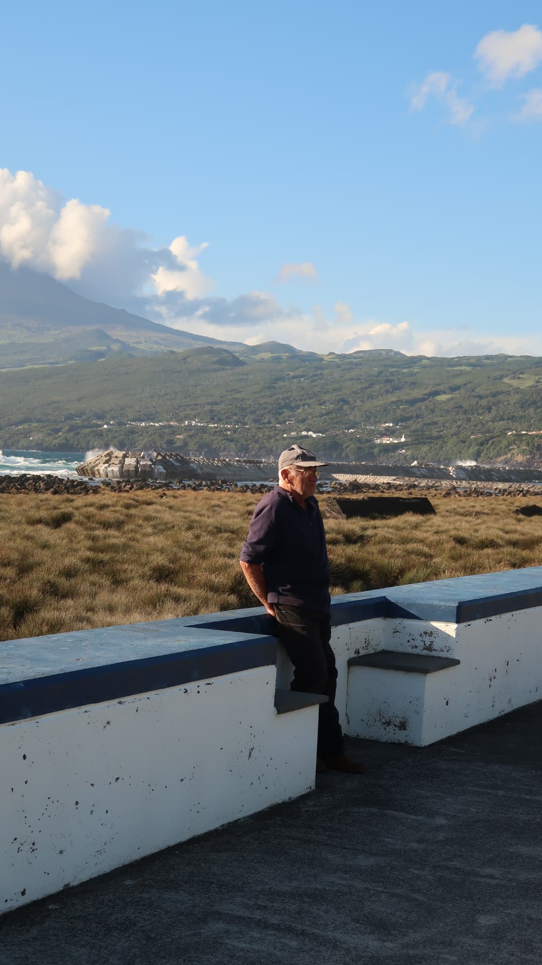 Man leaning on a blue and white sea wall with Pico behind
