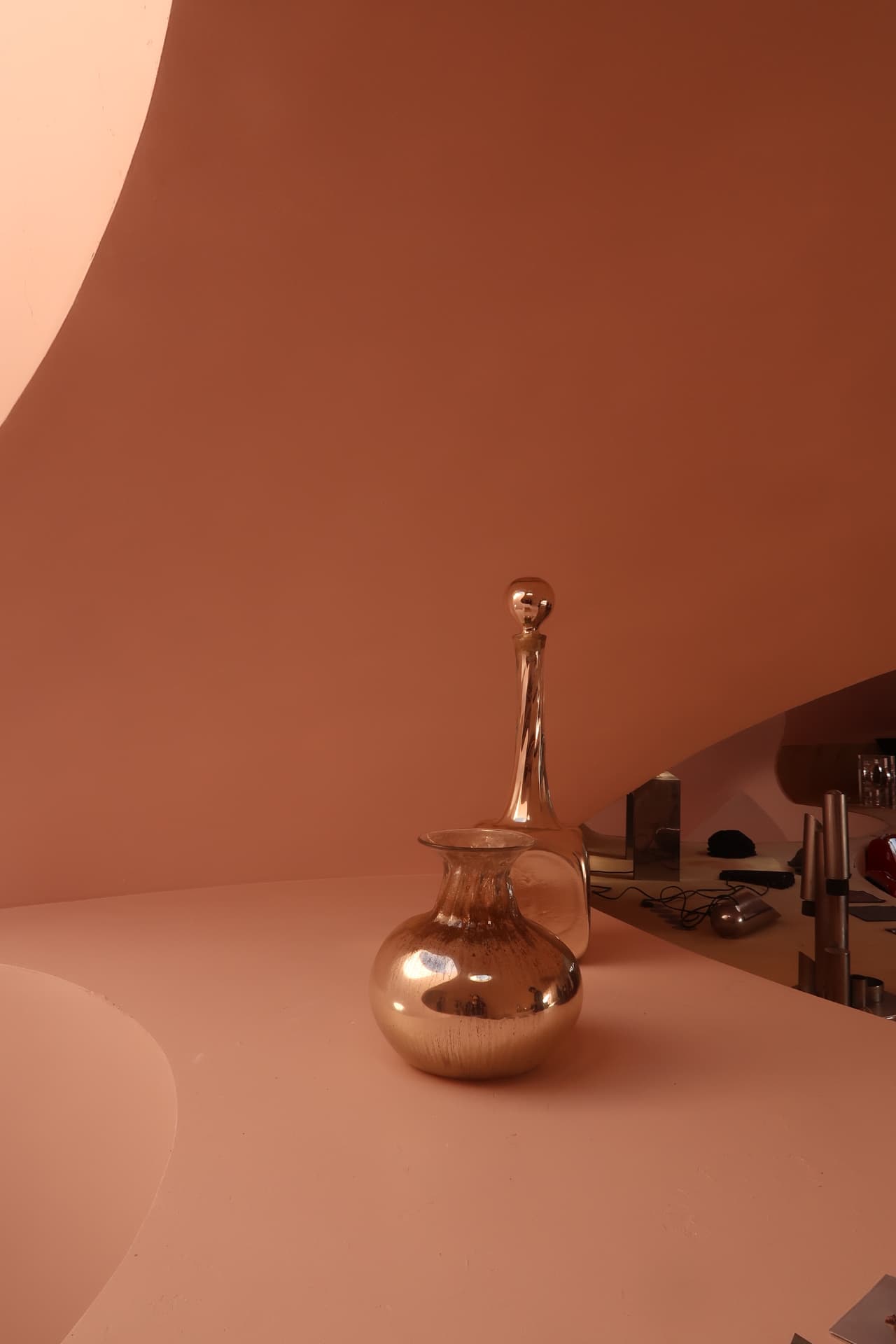 Gilded carafe and vase on a pink curved counter