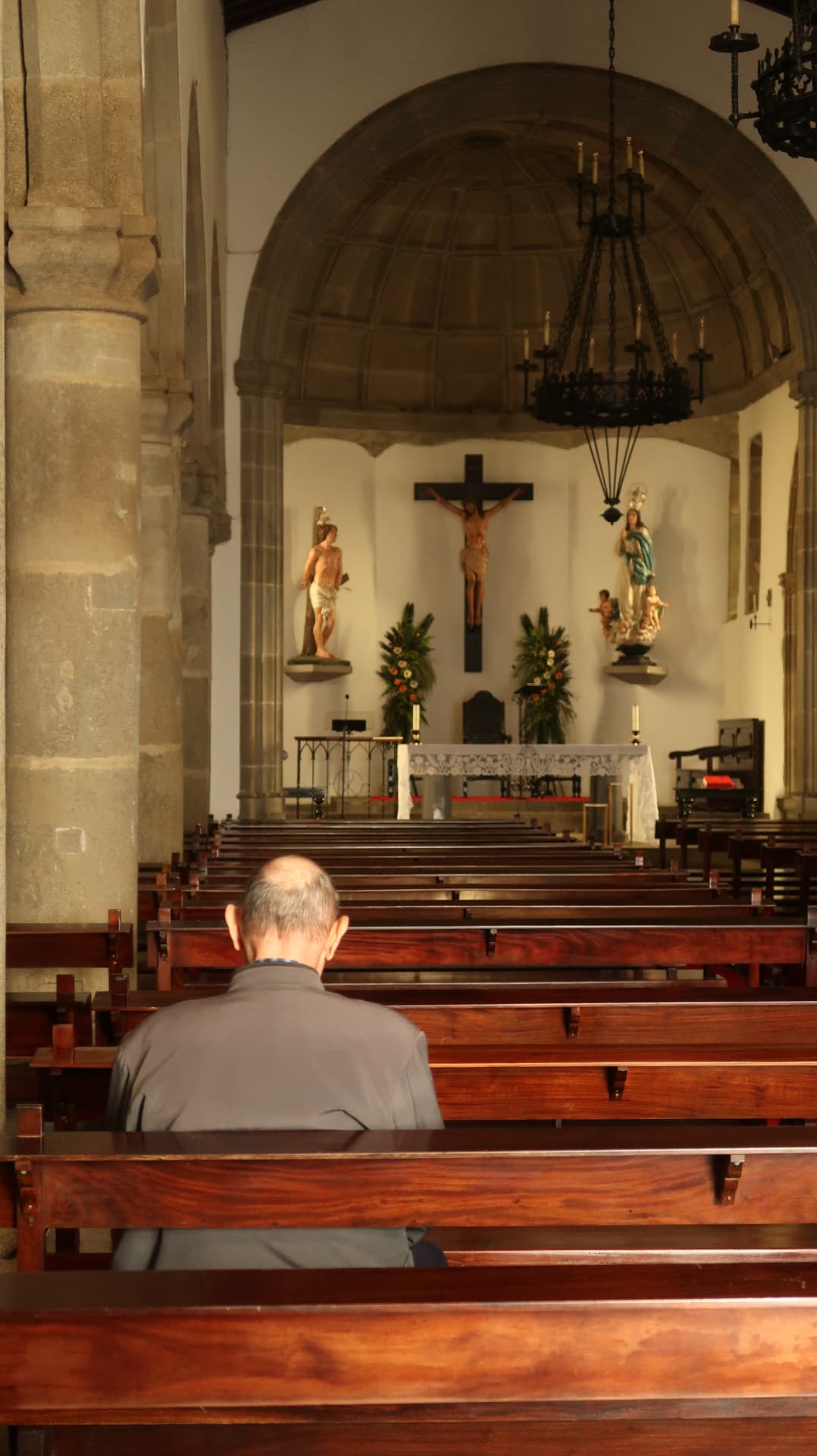 Man alone in a church pew facing the altar