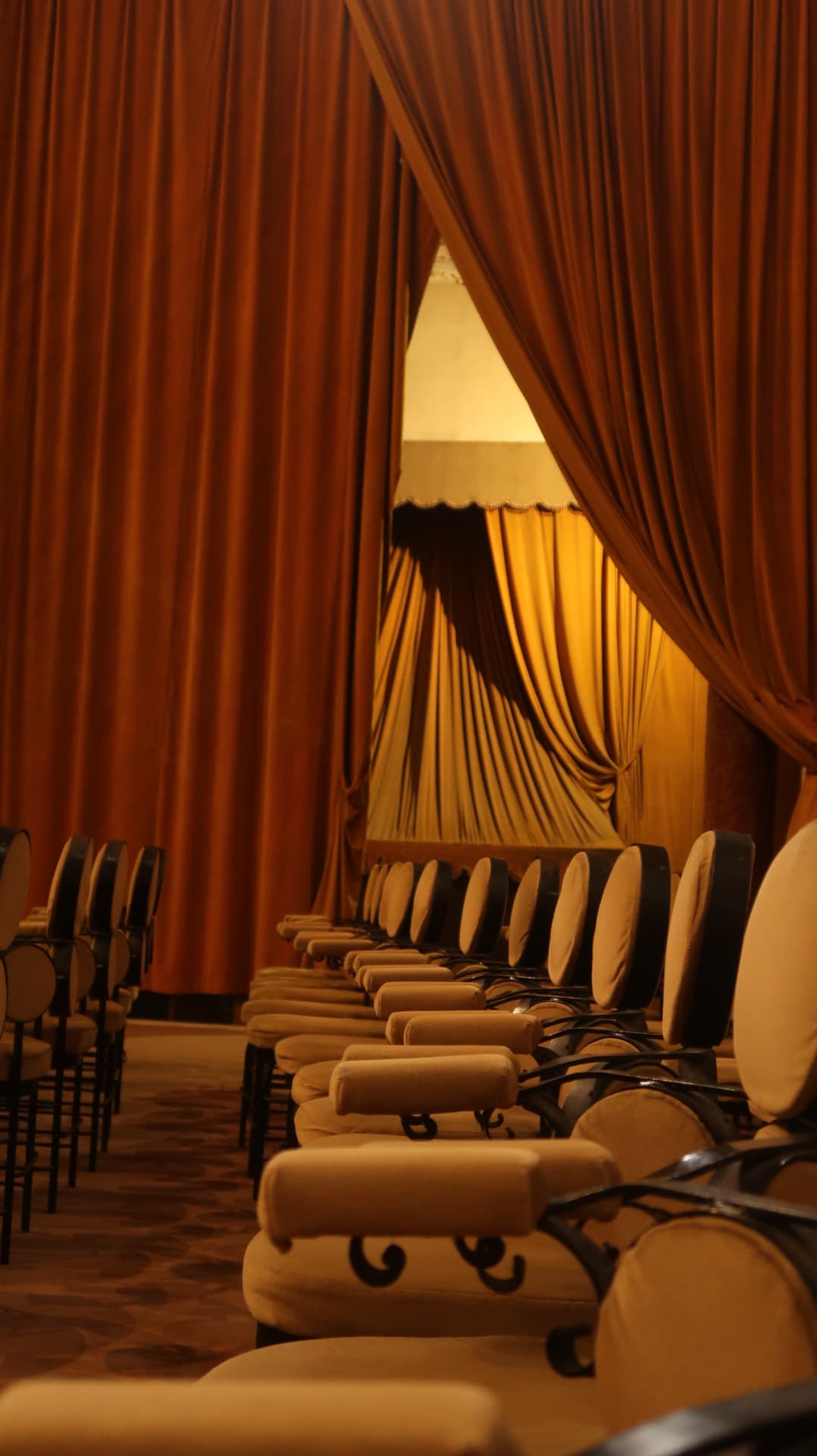 Draped rust curtains framing a lit alcove