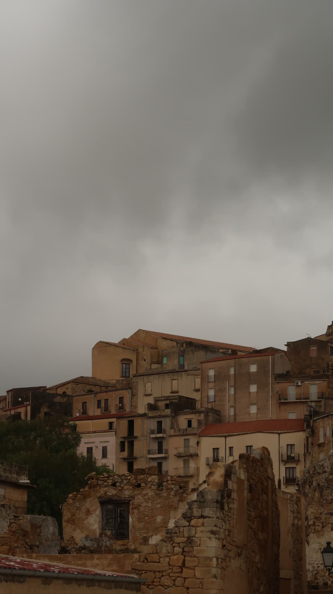 Hill town of ochre houses under a heavy grey sky